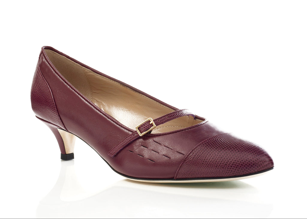 A single women's pump shoe in burgundy textured leather with a kitten heel and a small gold buckle detail, shown on a clean white background.
