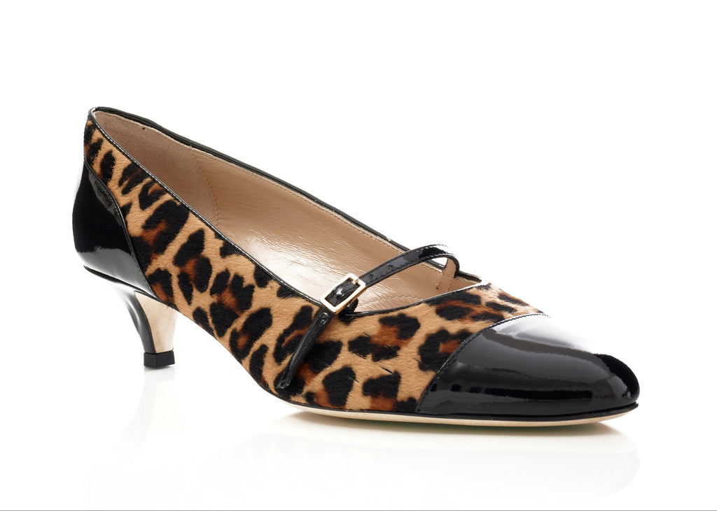 Black patent leather shoe with a pointed toe and thin heel on a white background